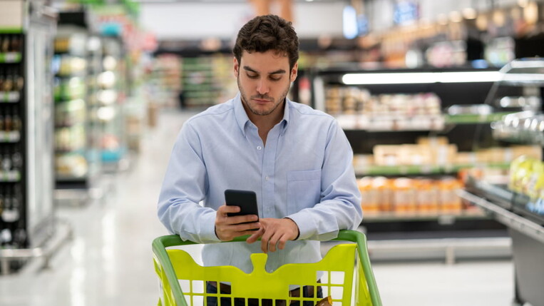 Mann bekommt Push-Nachricht im Supermarkt