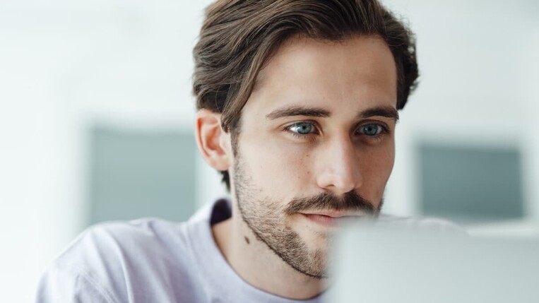 Mann guckt auf seinen Laptop