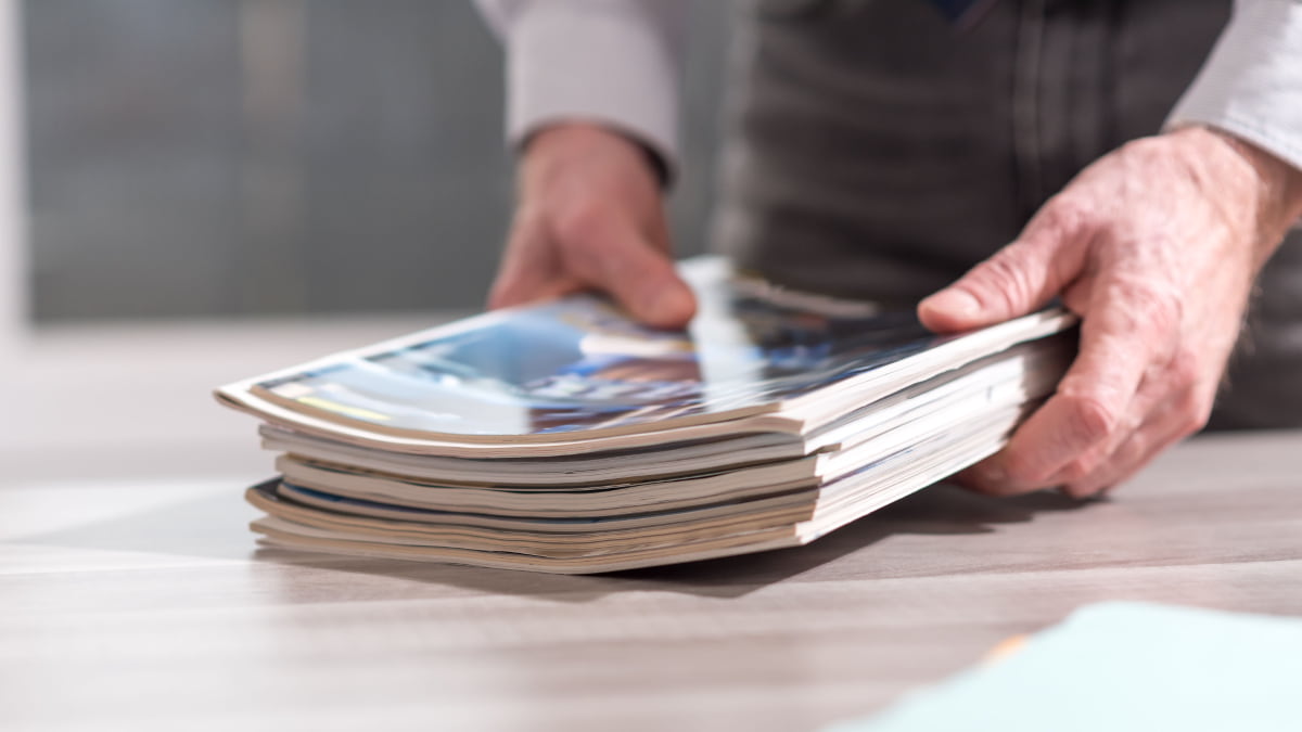 pile of magazines hold by a business man