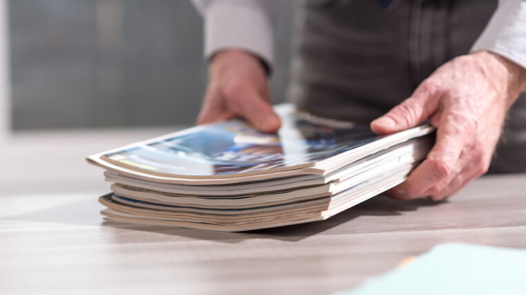 Pile of magazines held by a business man